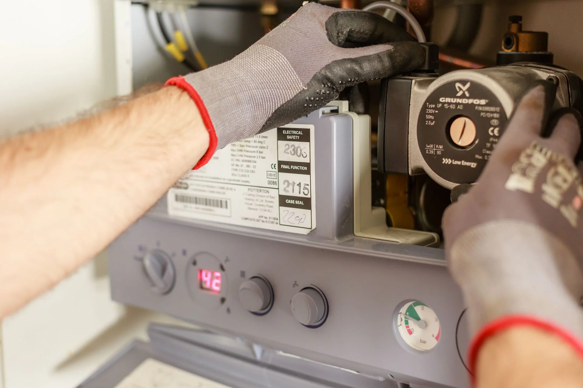 A technician's gloved hands servicing the inside of a heating unit