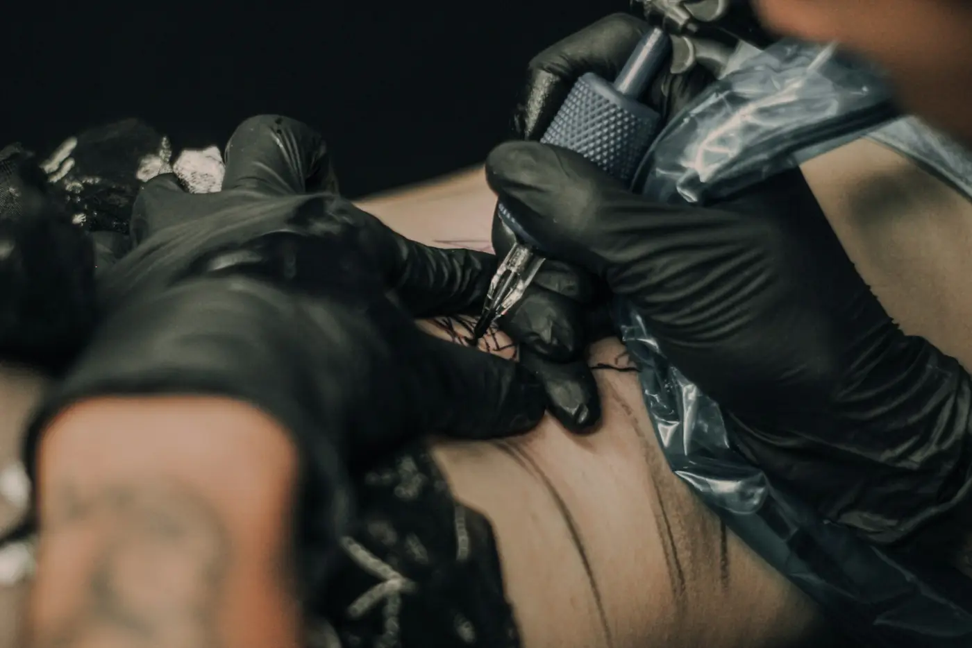 A tattoo being applied by a hand in a black glove